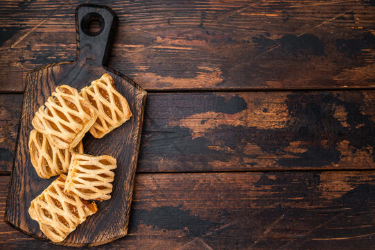Apple puff pastries with lattice crust on wooden board. Rustic baked dessert flatlay with copy space on dark background