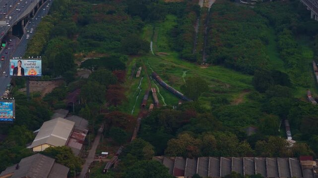 High aerial view showing old industrial area with a freight train on disused tracks next to bustling highway in Bangkok, Thailand. Bangkok, Thailand May 2. 2025