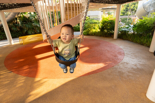 Asian child smiling on a swing at playground