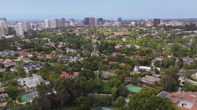 Affluent Beverly Hills neighborhood with luxury homes and mansions revealing Century City skyline in Los Angeles, California during day