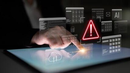 A hand interacts with a touchscreen displaying an alert icon and digital data elements,...