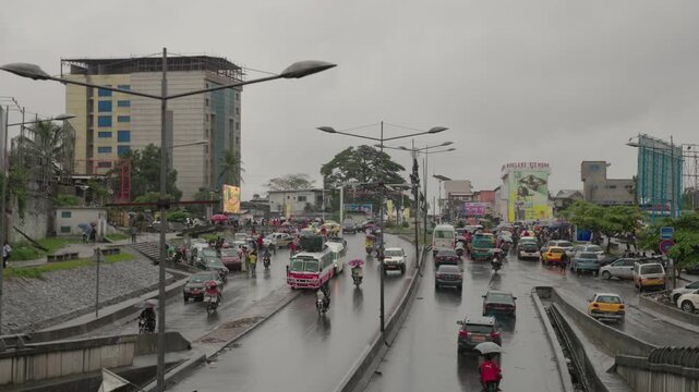 Douala, Cameroon - 26 May 2026: View of heavy traffic and pedestrians on a wet urban road under a cloudy sky in the city center.