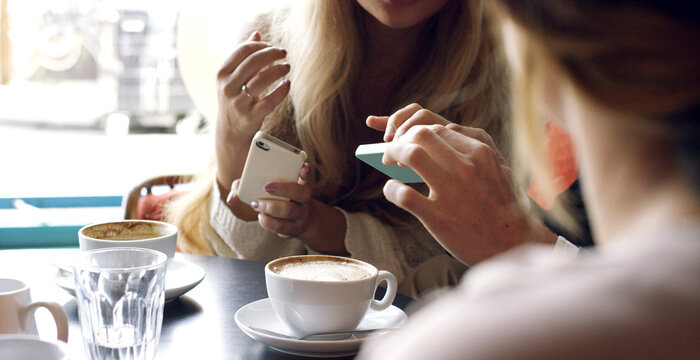 People, hands and phone with coffee in cafe for social media, communication or online news. Group, friends or network with mobile smartphone for internet or connection together in restaurant or shop
