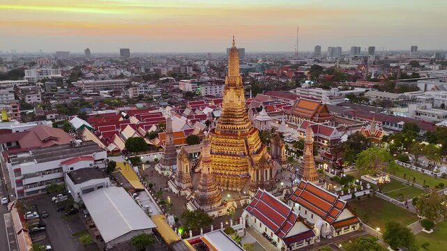 Aerial drone view of the famous Wat Arun temple also known as the Temple of Dawn, stands tall by the river Chao Phraya at night in Bangkok reflects the vibrant hues of the sunset against the cityscape