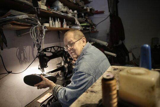 Elderly man repairing a shoe in his workshop