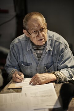 Elderly man with glasses filling out paperwork