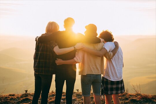 Group of friends with arms around each other at sunset