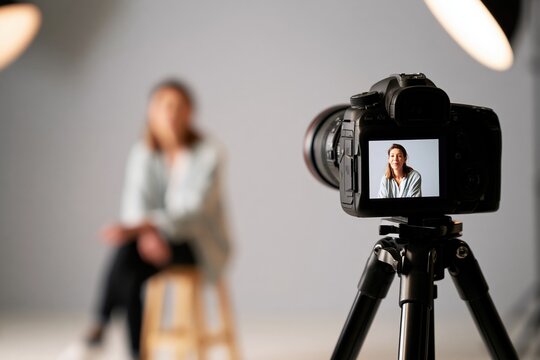 Recording woman in studio, dslr camera on tripod, creating content or capturing video for a vlog