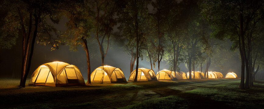A line of illuminated tents glows under the dark canopy of trees at night. A gentle mist enhances the atmosphere