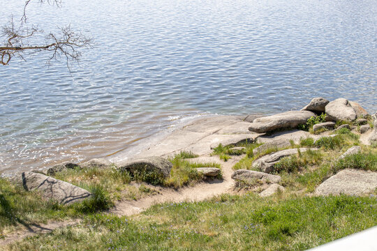 Sandy lakeshore with large stones in Borovoe, Kazakhstan. Natural landscape, travel and outdoor recreation concept.