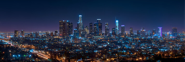 Fototapeta premium A stunning panorama showcases a bustling metropolis at night. Tall structures illuminate the sky, against a dark, starless backdrop