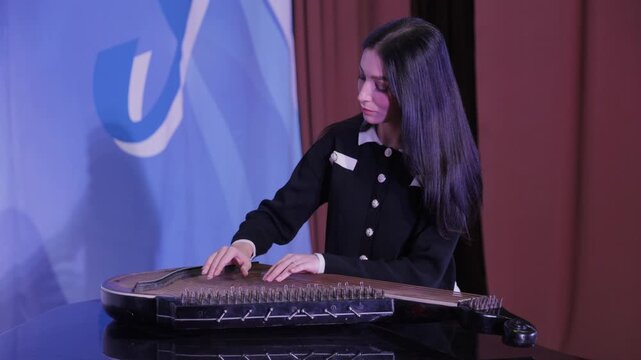 Young woman playing traditional ukrainian bandura instrument