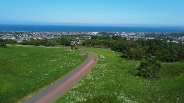 Aerial view of Edinburgh city landscape from Holyrood park showing coastal horizon and urban architecture in summer.