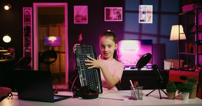 Cute child hosting internet show promotes wireless keyboard and mouse received from sponsoring brand. Little girl does influencer marketing, urging fans to purchase computer peripherals