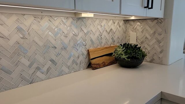 Modern kitchen counter with herringbone tile backsplash and warm lighting