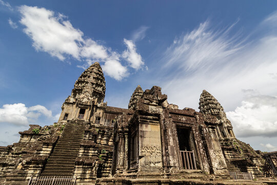 Low angle view of the ancient stone towers at the Angkor Wat second floor temple ruins under a bright blue sky
