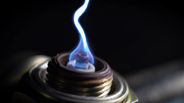 Macro view of a spark plug generating a bright blue electric spark for engine ignition on a dark background
