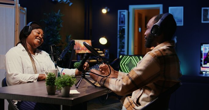 Show host adjusting analog mixer settings while talking with guest in studio, listening to opinion on current events. Influencer ensuring optimum sound quality while recording podcast