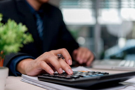 Financial accounting concept businessman calculating corporate budget tax and investment using calculator at office desk for financial planning and wealth management strategy
