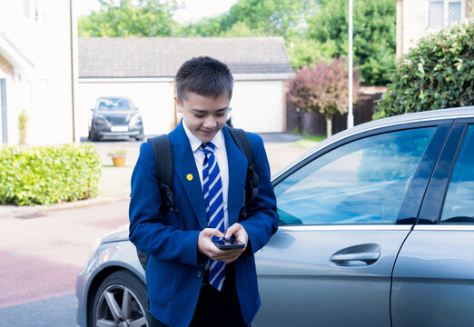 Student in school uniform using smartphone before class. Back to school, education, digital learning, mobile communication, student lifestyle, academic success and modern technology concept.