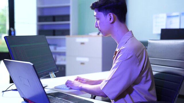 Male coder or developer working overtime using a computer display in problem solving at workplace.