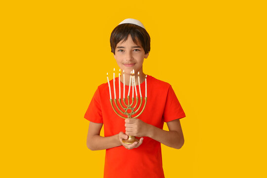 Little Israeli boy in kipa with menorah on yellow background
