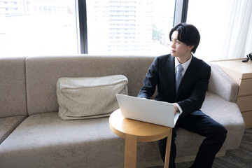 出張先のホテルでノートパソコンを使いオンライン会議などする若いビジネスマン © kapinon