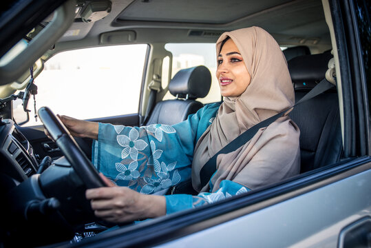 Beautiful woman in Dubai wearing abaya traditional female dress driving the car. Concept about uae and women rights