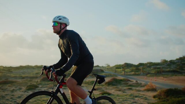 Athletic guy training cycling outdoors. Man in helmet riding bicycle, sport workout and healthy lifestyle.