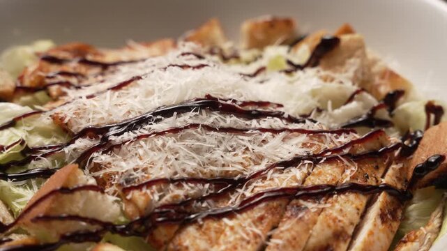 Delicious chicken caesar salad spinning in a white bowl with parmesan cheese and balsamic dressing, fa01
