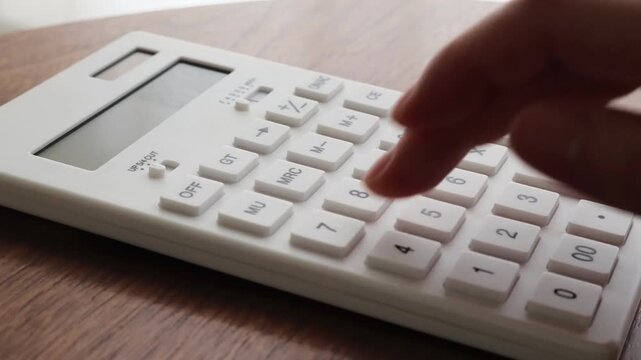 Hand Using White Calculator on Wooden Desk for Budget Calculation