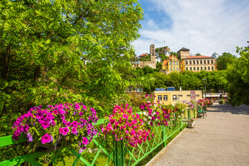 Obraz premium Scenic pedestrian bridge decorated with colorful petunia flowers overlooking old town in Jajce, Bosnia and Herzegovina