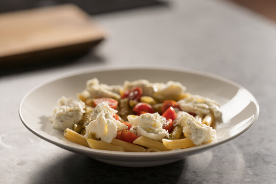Penne pasta with mozzarella, pesto and fresh cherry tomatoes
