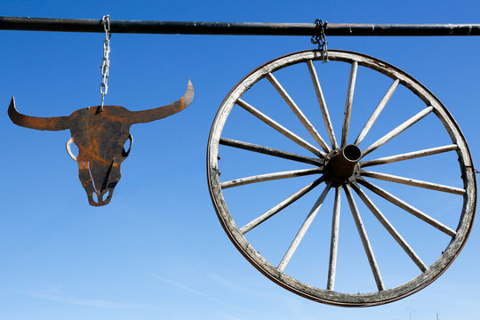 Old wagon wheel  and cow skull against a blue western sky