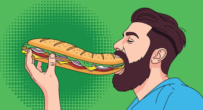 Hungry bearded man in a blue shirt is seen opening his mouth wide to eat a very long and delicious sub sandwich with fresh fillings.
