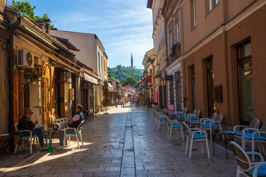 Sarajevo, Bosnia and Herzegovina, May 30, 2026, Scenic pedestrian street in Bascarsija old bazaar with outdoor cafes and distant view of a mosque minaret on a hillside