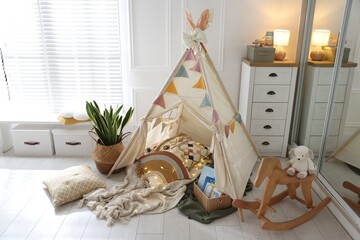 Cute wigwam with fairy lights and toys in stylish child's room © New Africa