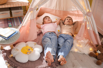 Little girl and boy lying in wigwam at home © New Africa