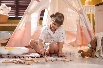 Little girl playing with building blocks in wigwam at home © New Africa