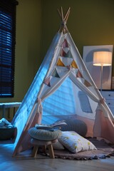 Beautiful wigwam, cushions and toys in child's room at night © New Africa