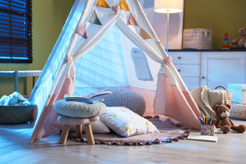 Beautiful wigwam, cushions and toys in child's room at night © New Africa