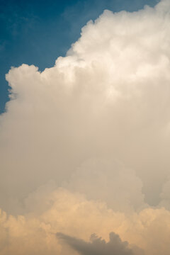 Fluffy white clouds illuminated by warm tones against a blue sky.