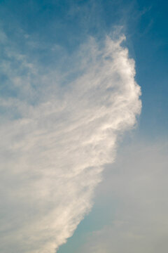 Wispy white clouds dancing against a blue sky on a serene day.