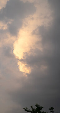 Mysterious cloud formation with golden hues contrasting dark stormy clouds.