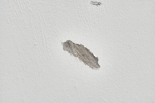 Close-up of a textured wall showing a patch of damaged plaster.