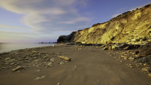 researcher viewpoint on eroded coastal shelf capturing exposed strata, scattered boulders, tidal markings and warm lateral light ideal for scientific