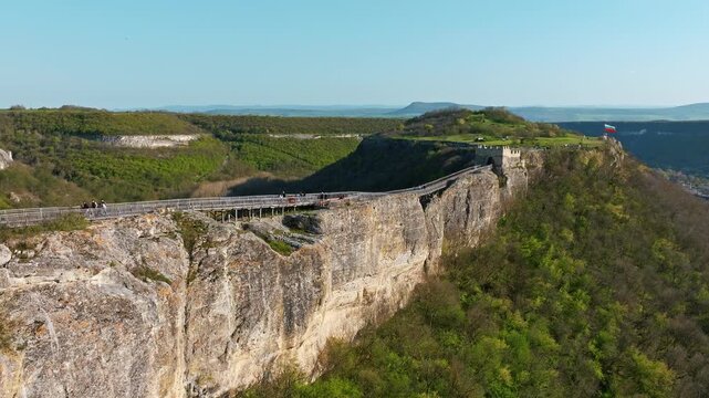 Ovech fortress long wooden eco path bridge on high rocky cliff edge green hills canyon landscape sunny day travel landmarks Provadia Bulgaria aerial view