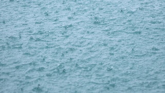 CLOSE UP, DOF: Dense tropical rain hammers the sea, covering the surface with tiny ripples and splashes. Glimpse of weather in wet season rolling across the Mentawai Islands and the Indian Ocean.