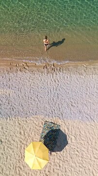 Aerial top down View of Woman with Yellow Umbrella Swimming in Aegean Sea Greece