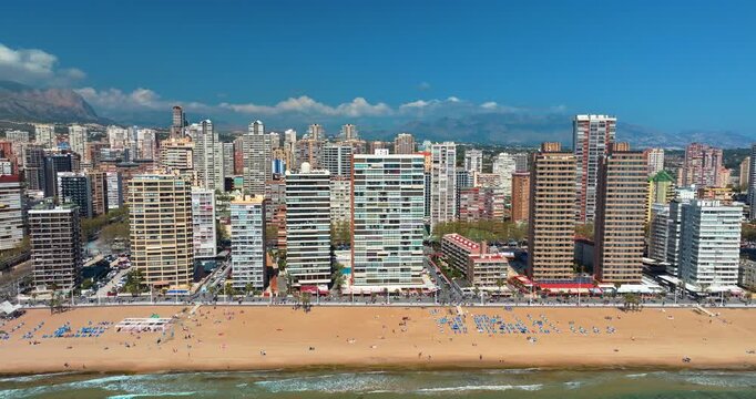 Benidorm Levante beach crowded summer season aerial drone shot Spain coastline apartment towers blue umbrellas turquoise sea tourists Mediterranean resort travel slow motion sunny day